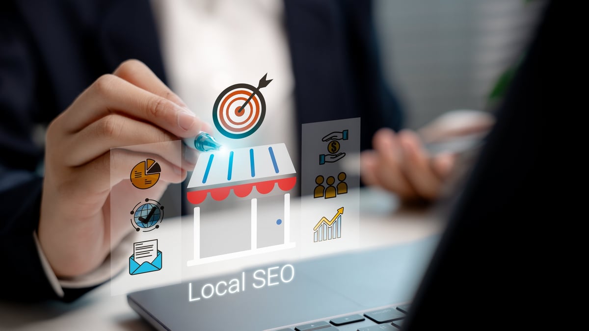 Businessman using stylus on virtual interface with local SEO icon and storefront graphic